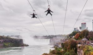 People ziplining above Niagara Falls with panoramic gorge views and mist rising below