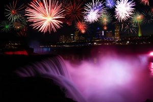 Niagara Falls illuminated with colourful lights at night, reflecting on the water below